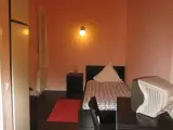 Cama individual entre una mininevera negra y una mesilla blanca en paredes azul claro